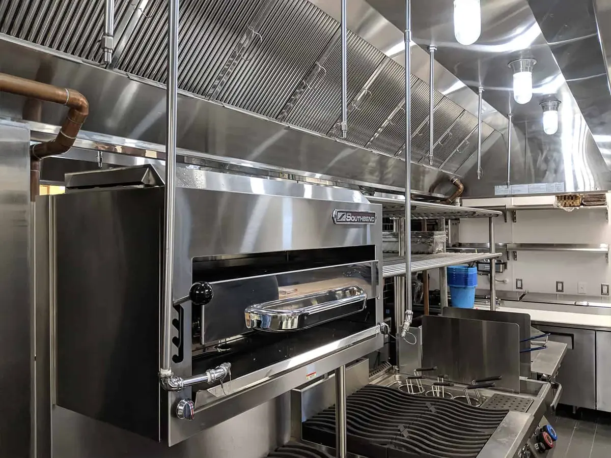 Completed stainless-steel commercial kitchen hood and cooking line
